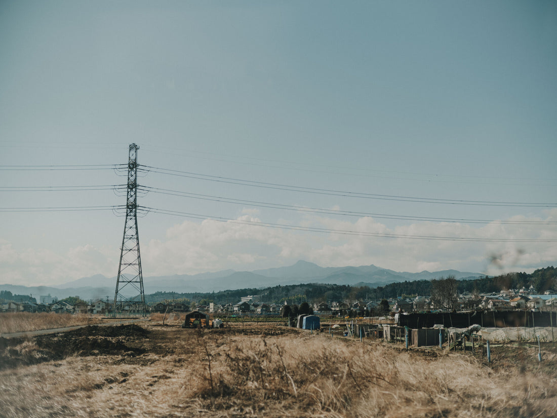 送電鉄塔の立つ田園と、遠くに広がる住宅地